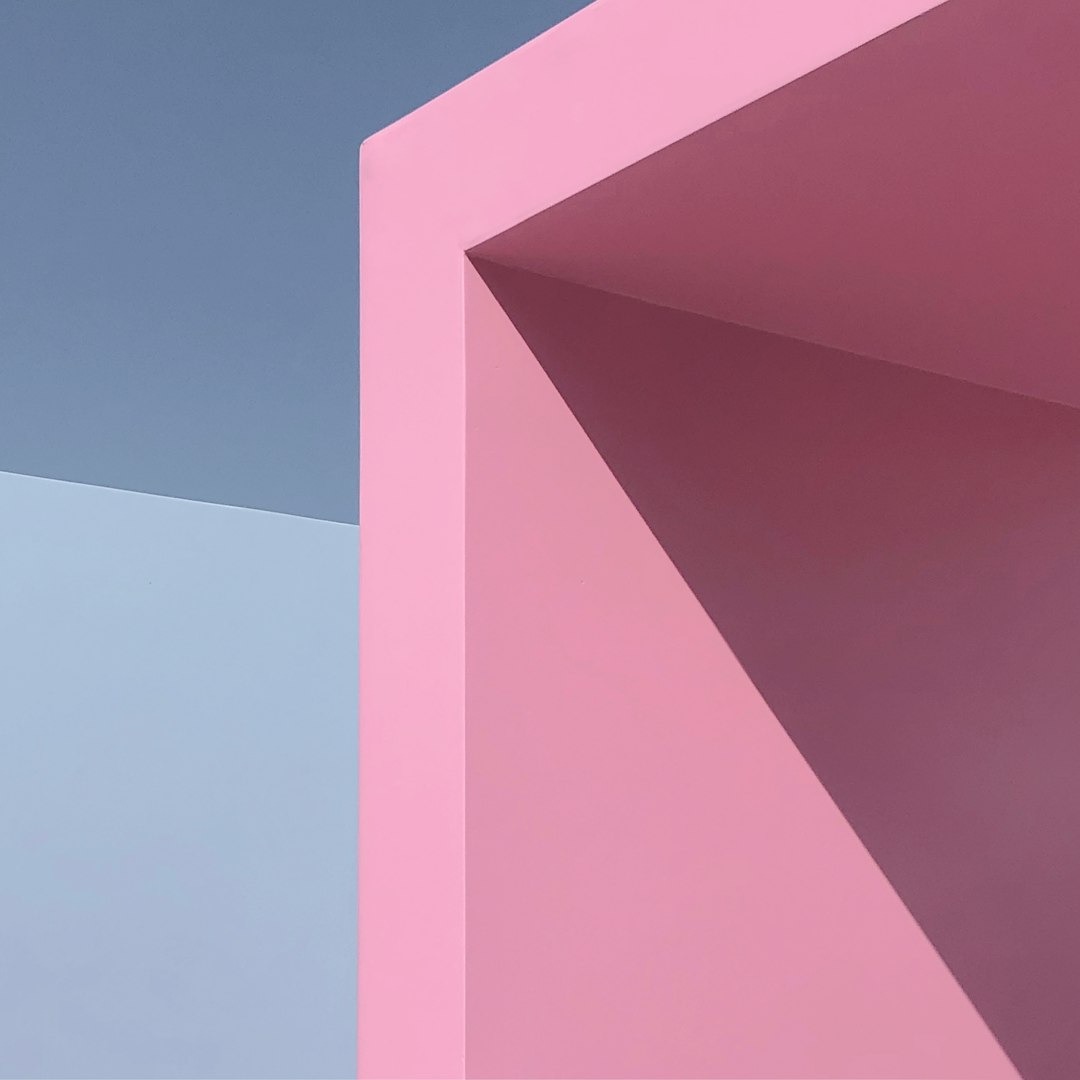 Pink and blue geometric shapes overlap in a minimalist composition.